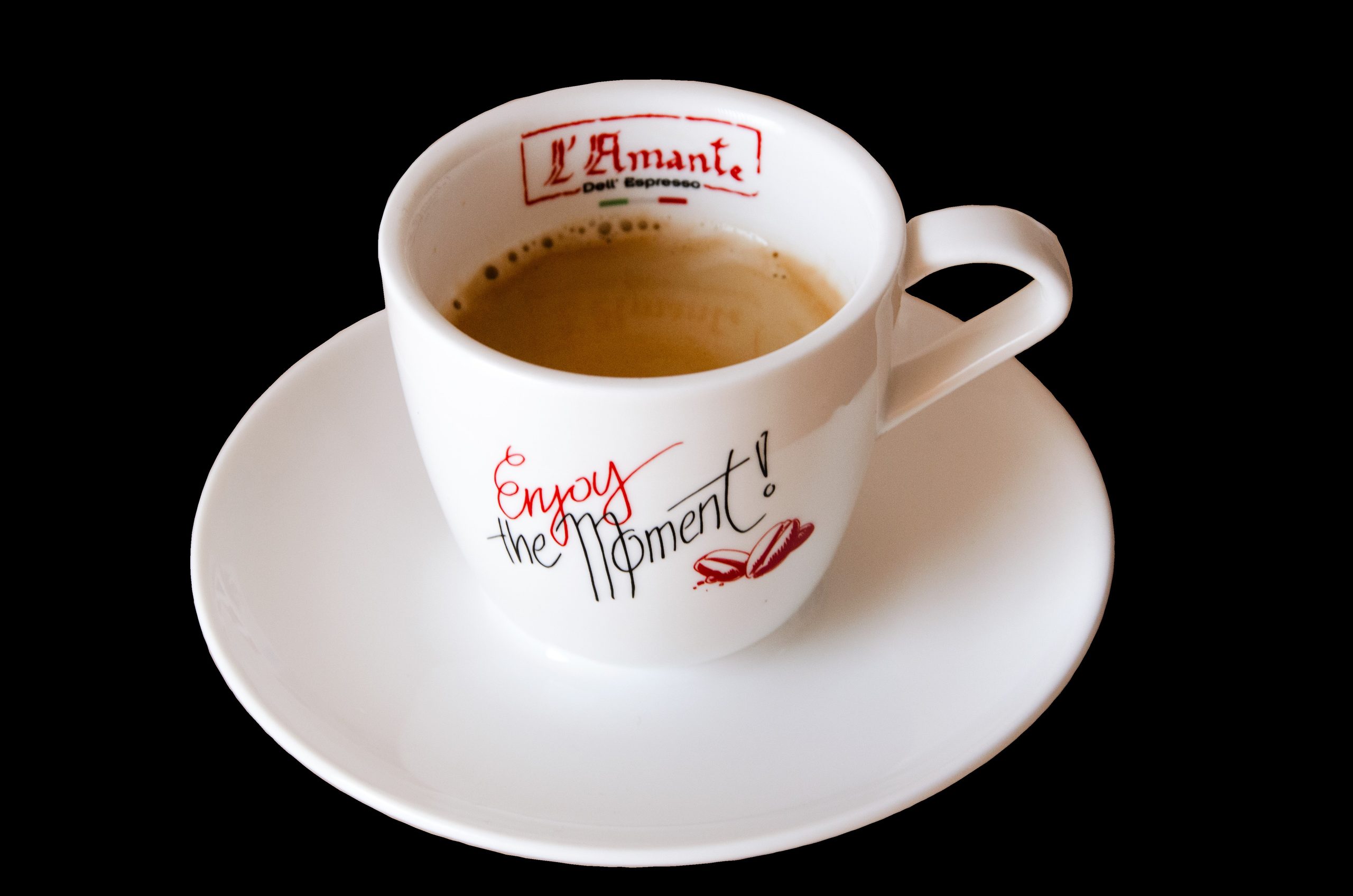 White ceramic coffee cup on a matching saucer, partially filled with coffee, against a black background with red script text on the cup.